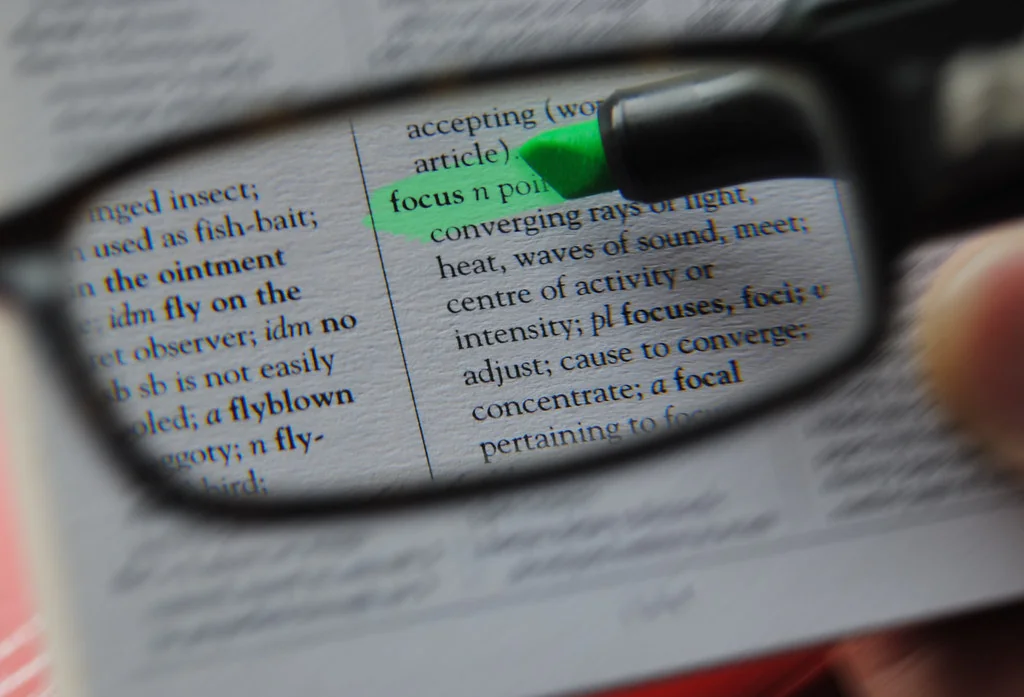 Dictionary page seen through glasses with the word focus highlighted