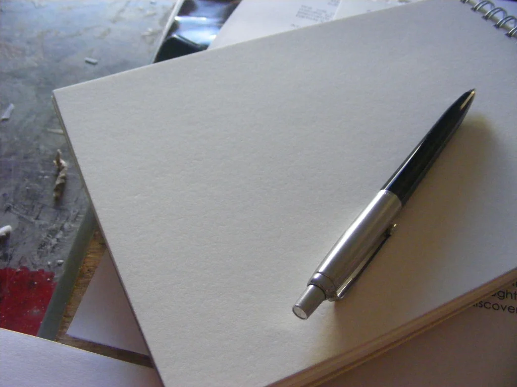 Pen resting on a blank spiral notebook