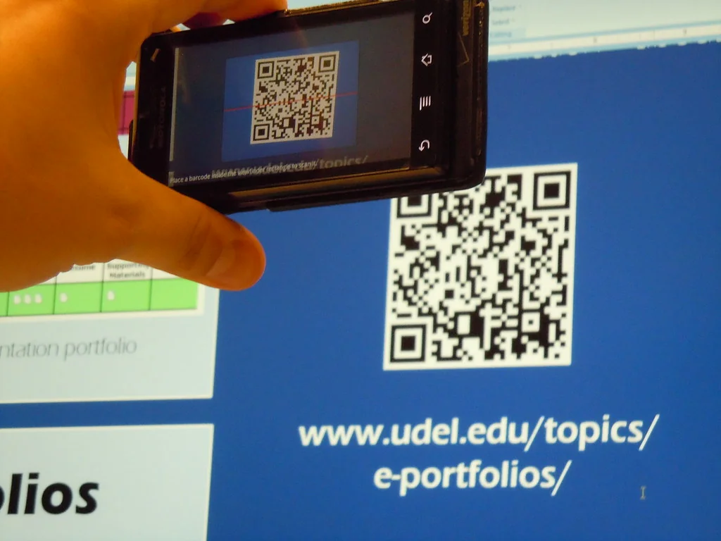 Phone camera scanning a QR code displayed above its printed web address