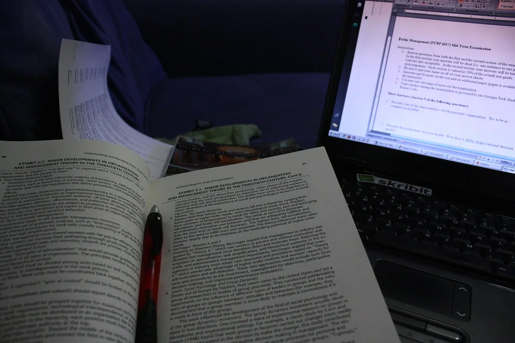 Open textbook and pen next to a laptop showing a document